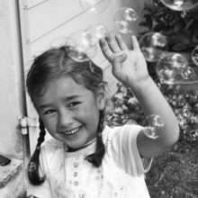 fillette qui se protège en riant nuage de bulles de savon