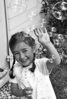 fillette qui se protège en riant nuage de bulles de savon