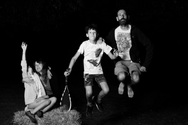 Photo de famille avec lumière artificielle dans la nature, posant en sautant d'une botte de foin